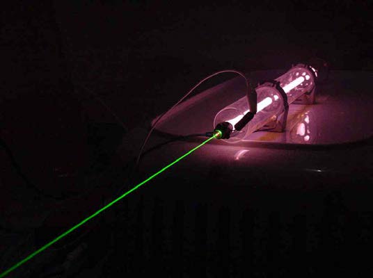 Below: Conventional HeNe tube laser within which the emission end contains a 95% mirror and the rearward oriented full reflectance 100% mirror, or ‘back mirror’. The HeNe is the gain medium which builds near instant cohe