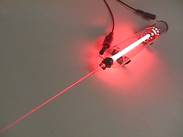 Below: Conventional HeNe tube laser within which the emission end contains a 95% mirror and the rearward oriented full reflectance 100% mirror, or ‘back mirror’. The HeNe is the gain medium which builds near instant cohe
