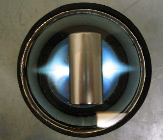 Top-down photograph of a cylindrical magnet centered on a circular Ferrocell, illuminated blue at both sides.