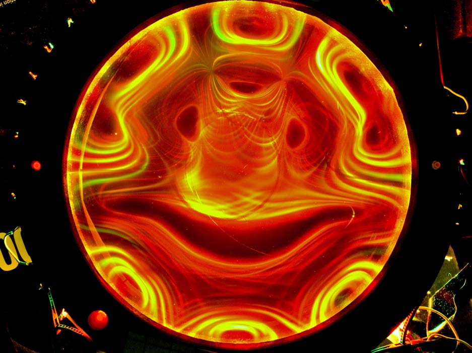 Circular Ferrocell photographed in red and yellow light, showing nested symmetrical field-line bands.