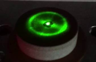 Third close-up of a circular Ferrocell glowing green above a magnet.