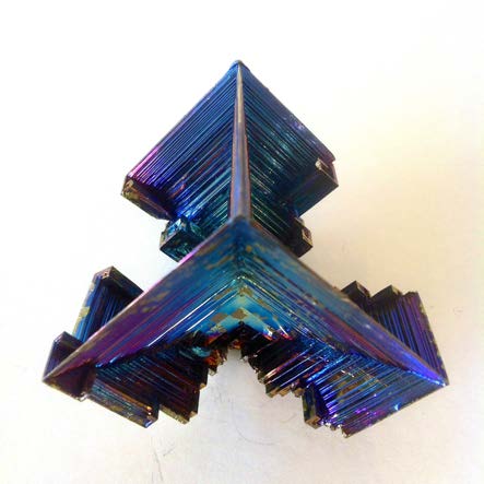 Side view of an iridescent bismuth crystal with angular, stepped projections.