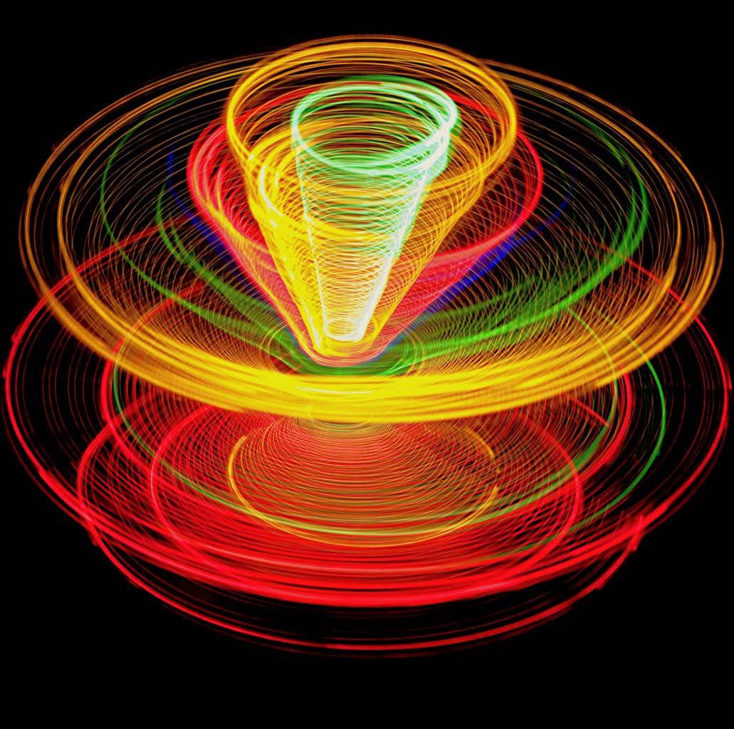 Multicolored light trails forming nested toroidal rings and a central funnel on black.