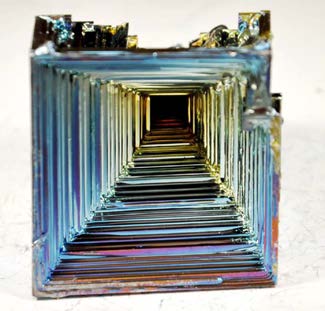 Square iridescent bismuth hopper crystal with inward-stepped terraces.