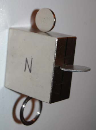 Below: 2x2x1” block neodymium, sitting on top is a disk magnet, on the side is a steel disk, sitting perpendicular to the dielectric inertial plane, bottom is a steel ring with a knife-thin edge also sitting perpendicula