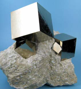 Metallic cubic iron-pyrite crystals growing from a rough stone matrix.